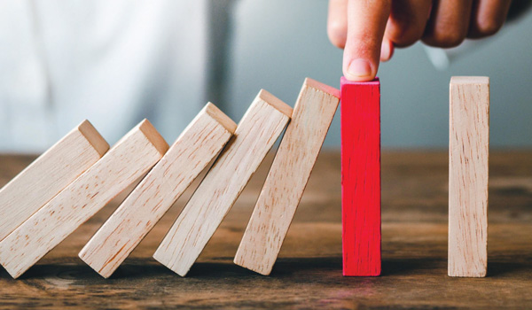 Standing blocks falling into one that's being propped up by someone's finger
